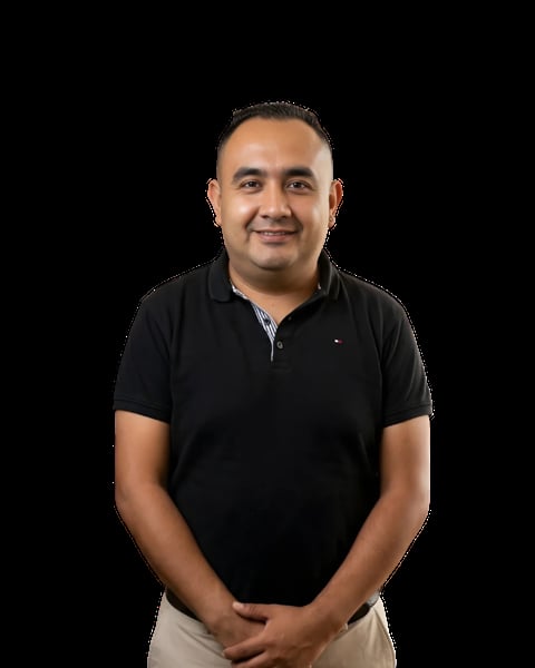 Portrait of a smiling man wearing a black polo shirt and khaki pants against a black background